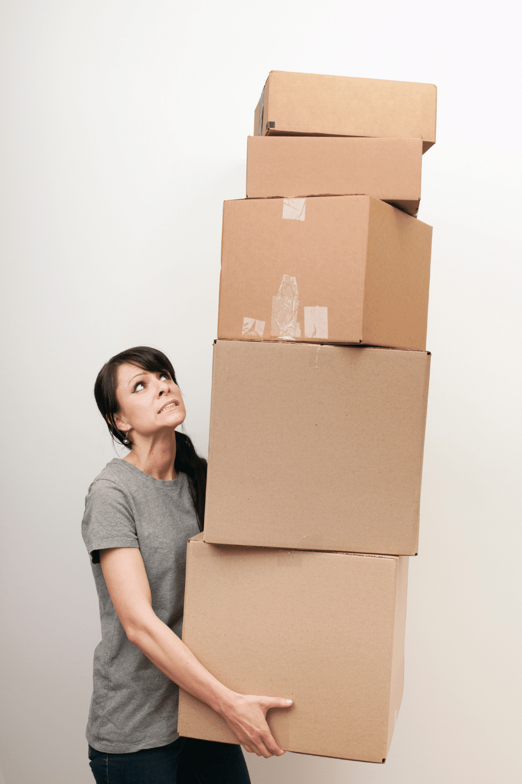 Woman struggling to balance stacked moving boxes during a stressful relocation